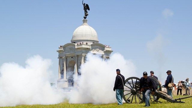 A group of United States soldiers use a cannon in front of the Pennsylvania Memorial. 